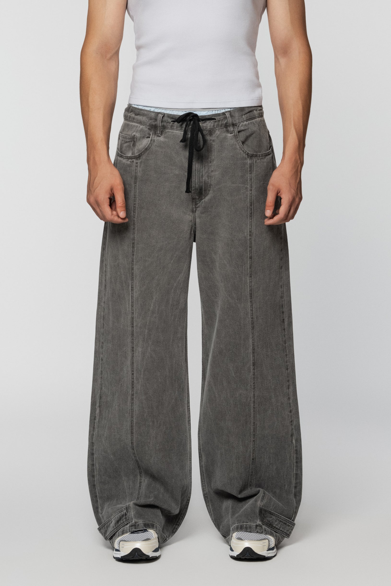 Loose grey jeans with tucks and a drawstring belt