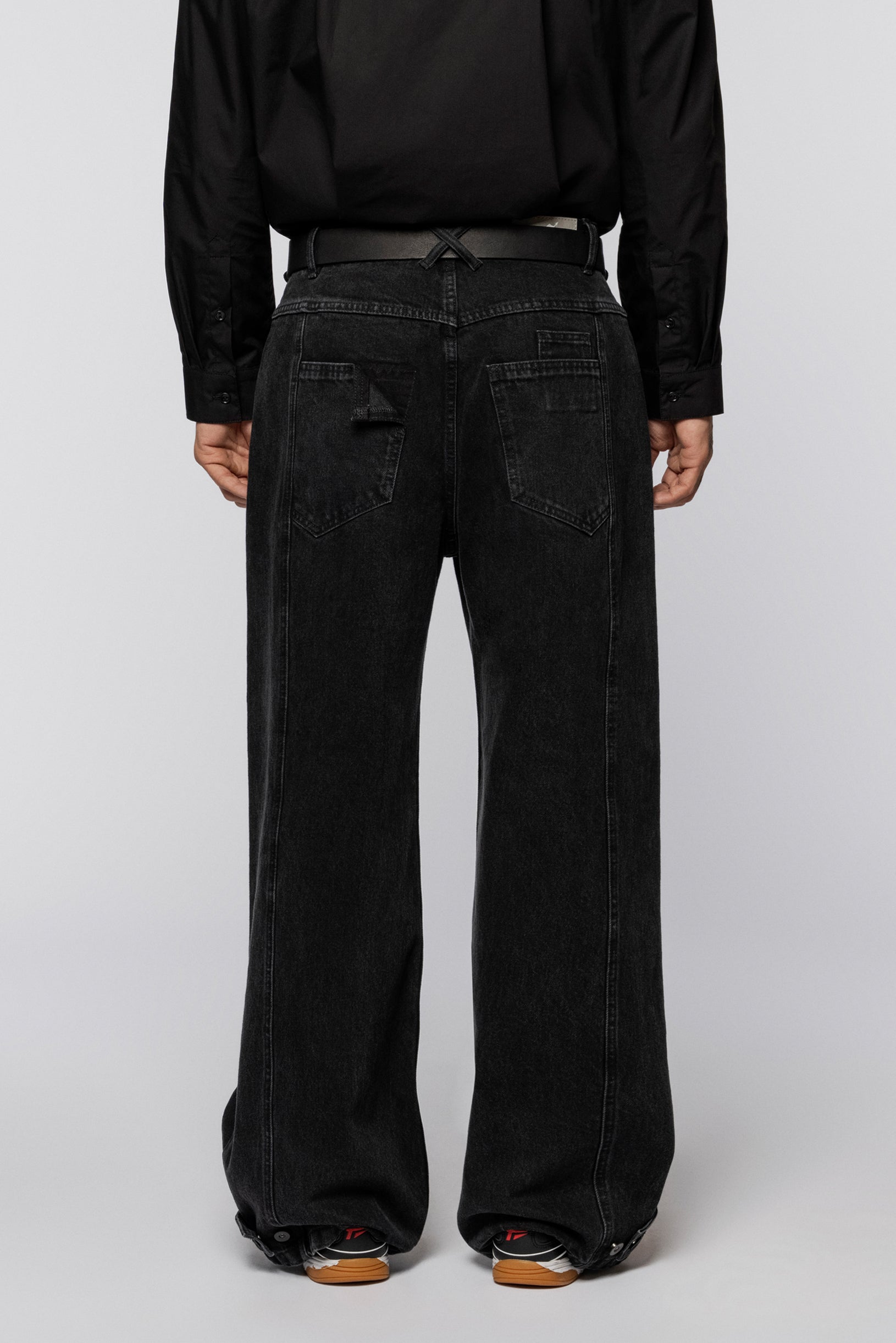 Black wide jeans with a washed effect and snap fasteners at the hem